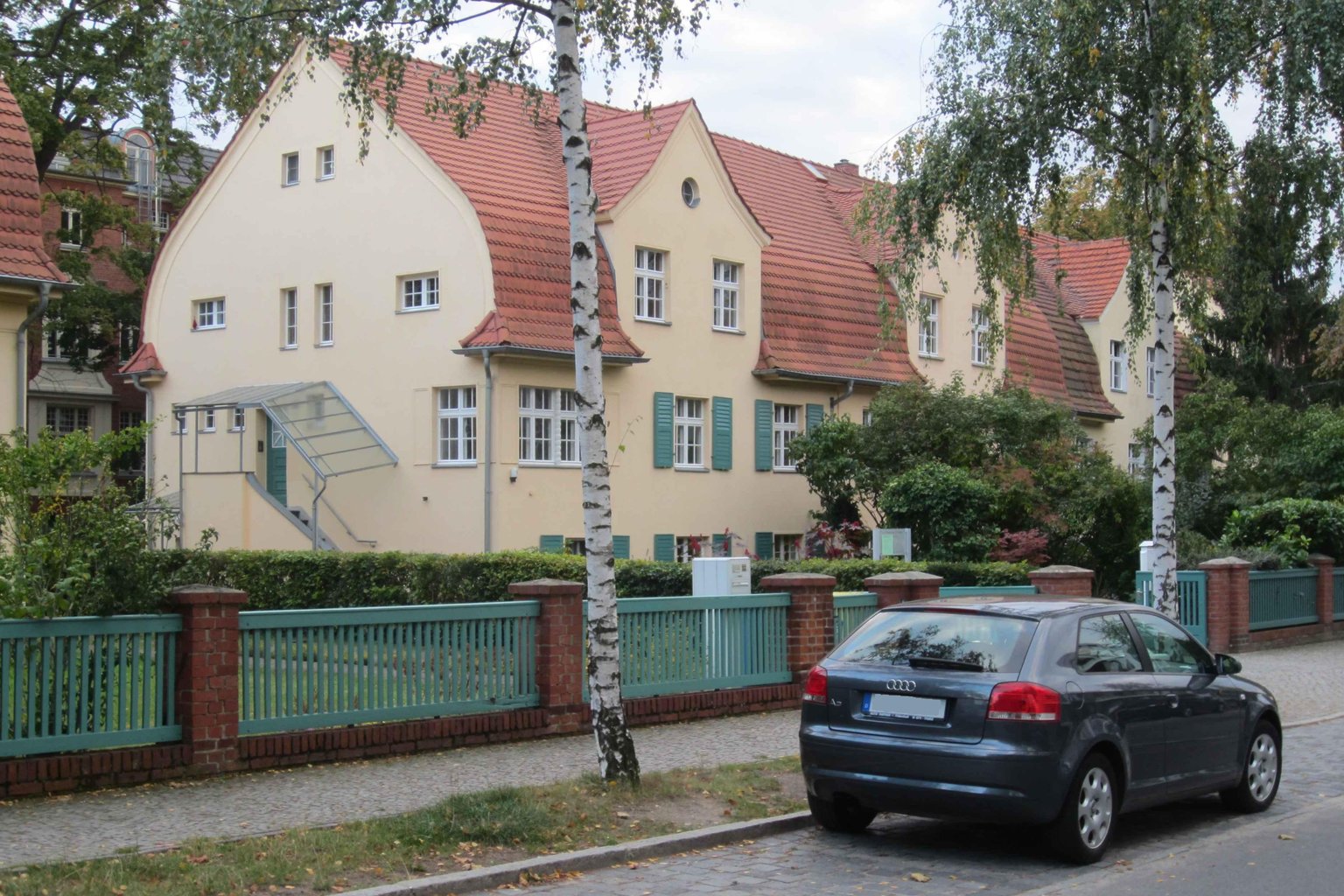 Denkmalgeschützte Wohnhäuser mit roten Ziegeldächern in der Leiblstraße in Potsdam, davor ein Gartenzaun