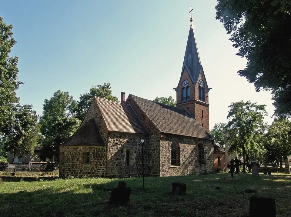 Die Dorfkirche Großziethen aus Feldsteinen mit Backsteinturm, umgeben von Bäumen und dem Kirchhof