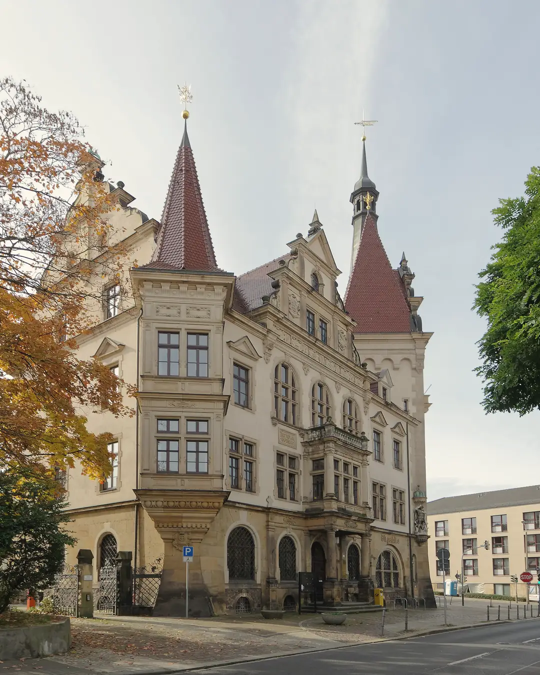 Das Rathaus im Dresdner Stadtteil Plauen mit Türmen und Ziergiebeln, Eckansicht an der Nöthnitzer Straße, links ein Baum mit Herbstlaub