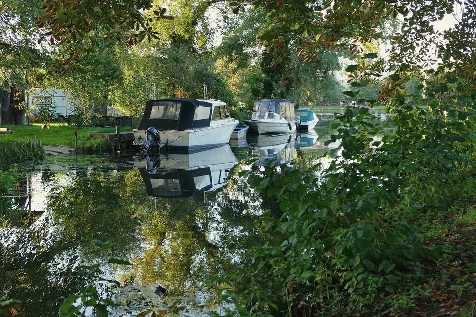 Motorboote an Stegen im Bretterscher Graben, umgeben von Grün