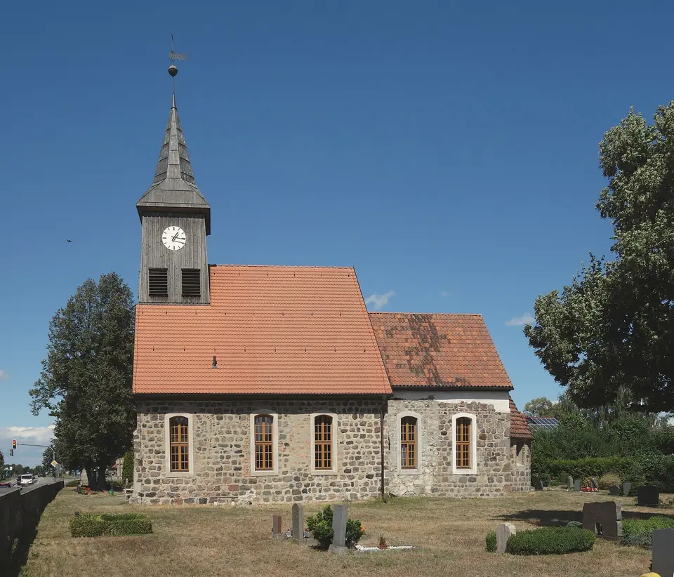 Die Dorfkirche Seeburg aus Feldsteinen mit rotem Ziegeldach und hölzernem Turm unter blauem Himmel