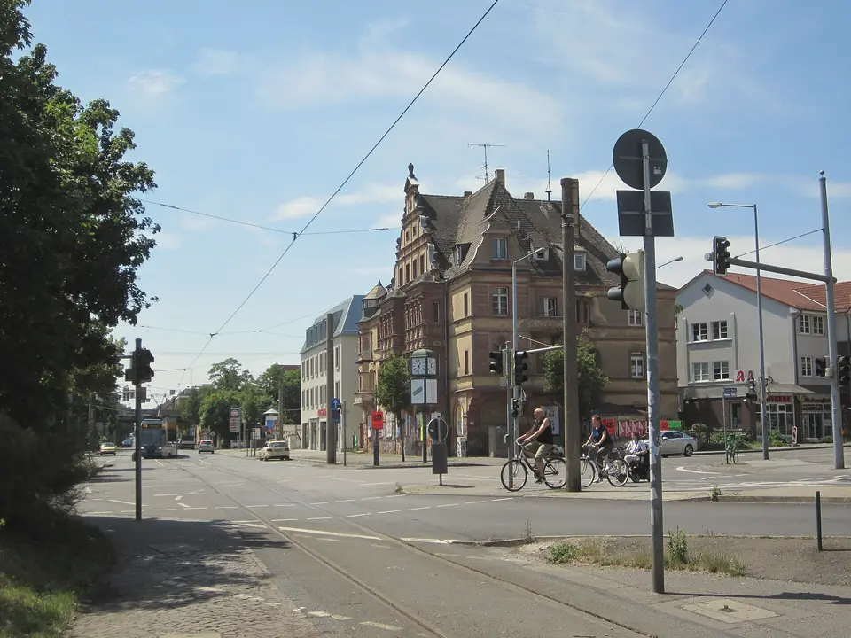 Die Kreuzung an der Post in Mockau mit Straßenbahngleisen, Radfahrern und einem Eckhaus mit Giebeln