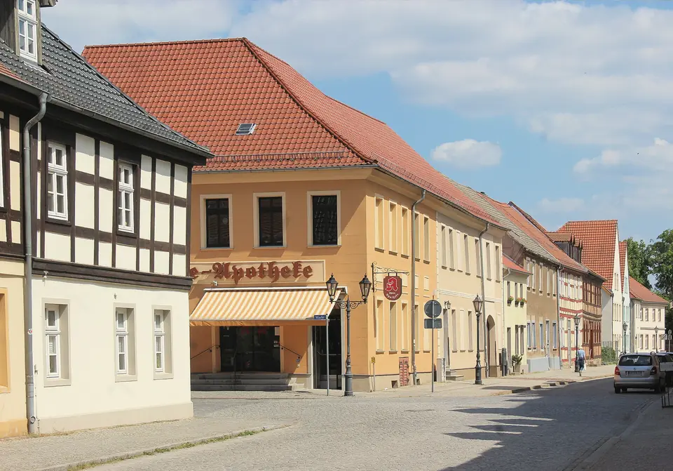 Die Bodelschwinghstraße in Beeskow mit einem Fachwerkhaus, einer Apotheke und Häusern mit roten Ziegeldächern