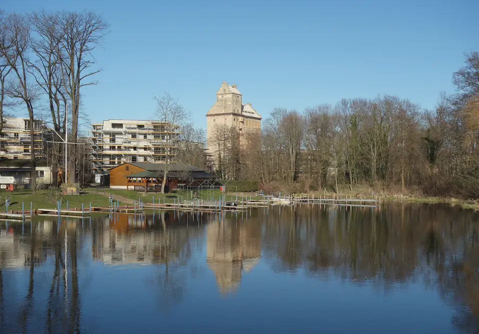 Der Getreidespeicher in Oranienburg hinter einem Gewässer, in dem sich Bäume und Häuser spiegeln