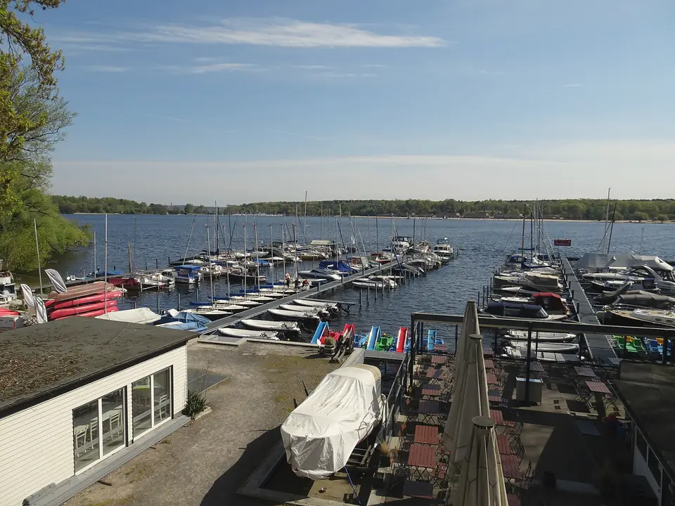 Bootshafen am Großen Wannsee mit Segel- und Motorbooten, dahinter Wasser und Waldufer