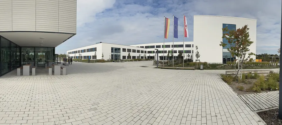 Der gepflasterte Schulhof der Geschwister-Scholl-Gesamtschule in Dabendorf mit hellen Neubauten und Fahnenmasten