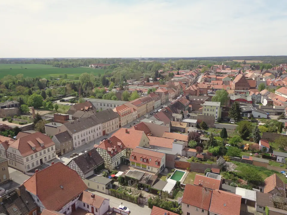 Blick von der Aussichtsplattform der Nikolaikirche über die roten Dächer der Altstadt von Jüterbog, im Hintergrund Felder und Wald