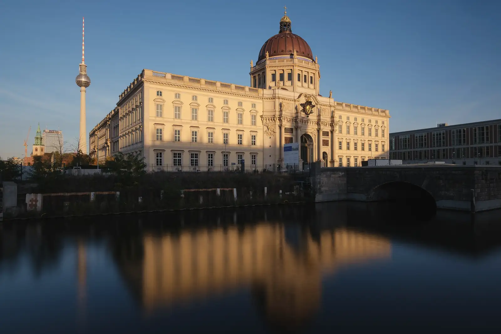 Humboldt Forum mit Kuppel und Fernsehturm in Berlin-Mitte, davor gespiegelt im Wasser