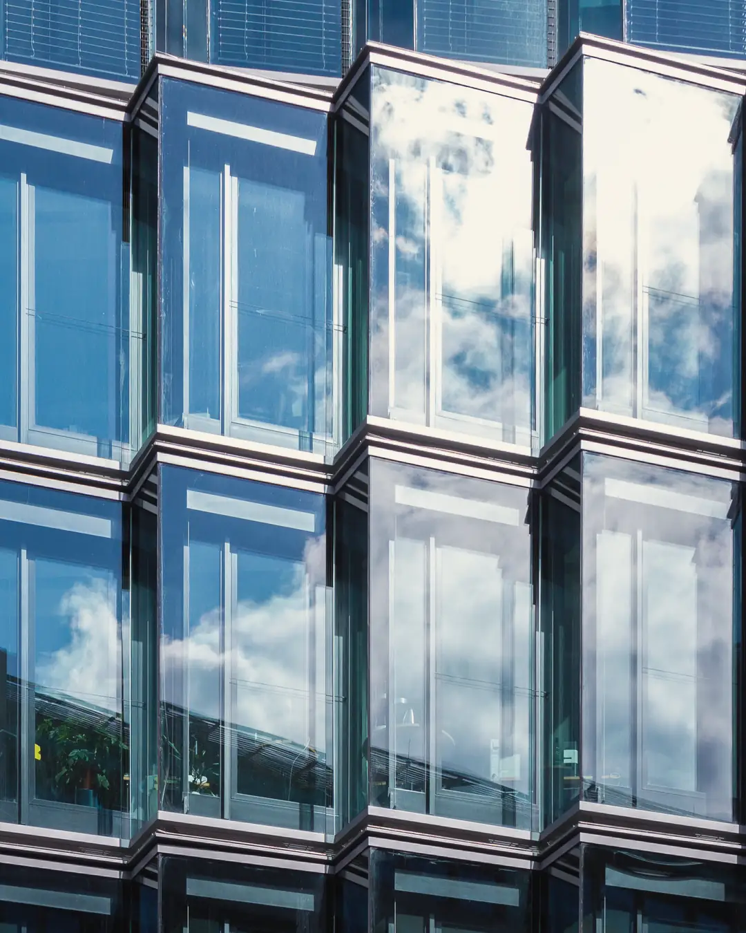 Glasfassade eines Bürohauses in der Wilhelmstraße in Berlin-Mitte, in den Fenstern spiegeln sich Wolken